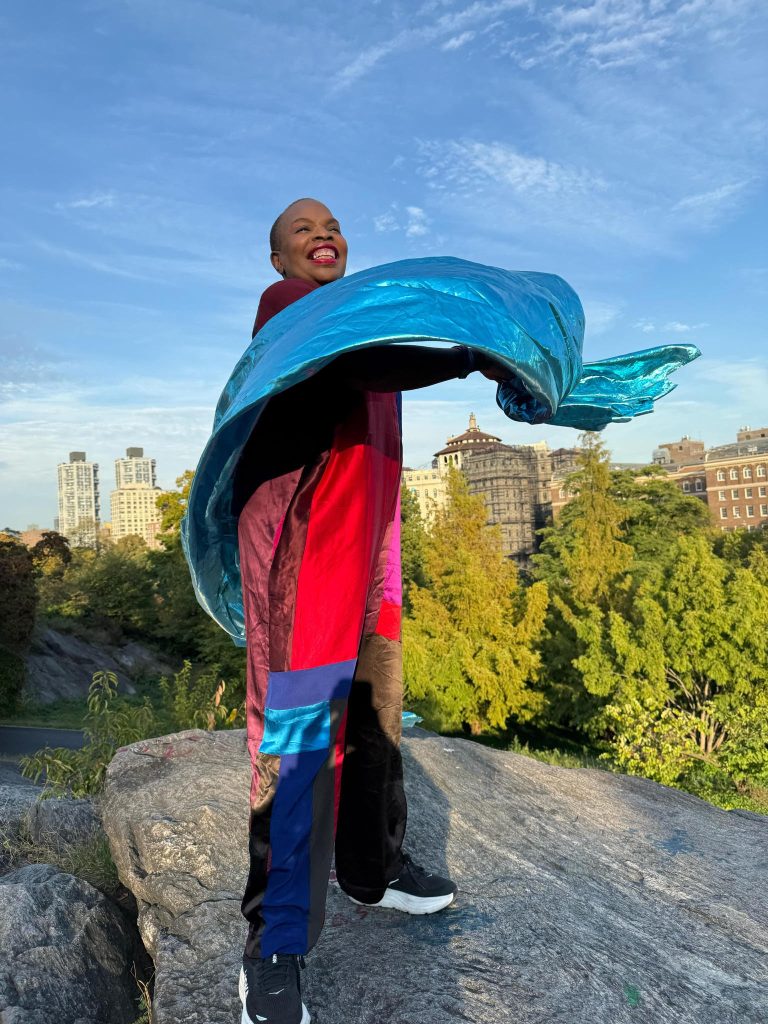 Image of Hazel, standing on a rock and waving a colorful piece of cloth.